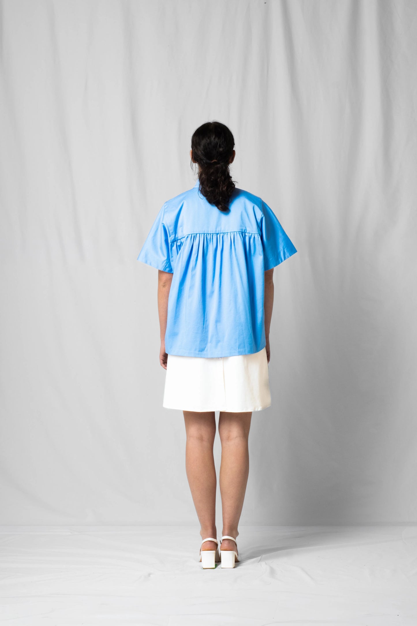 Ciel blue short-sleeve Bowie shirt with button fastening and gathered detailing from the SS26 collection by STEF SERIES shown from the back.