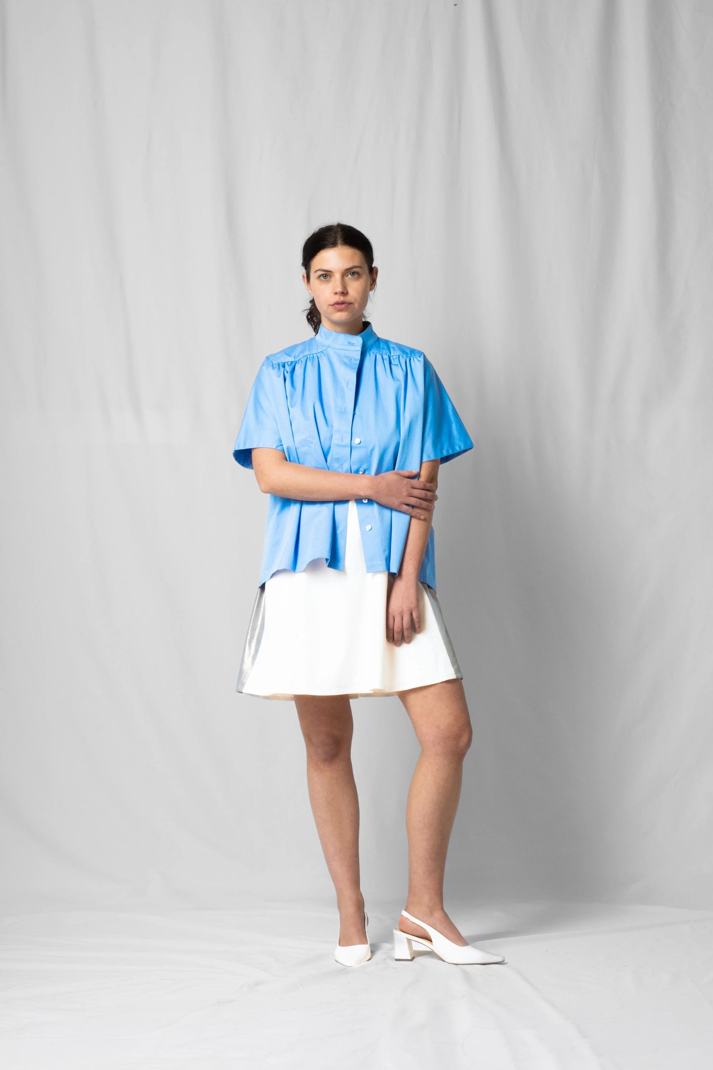 Model wearing the ciel blue short-sleeve Bowie shirt with button fastening and gathered detailing from the SS26 collection by STEF SERIES.